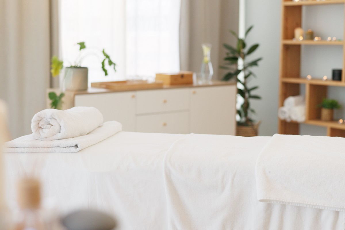 A serene spa room with a massage table and neatly folded towels.
