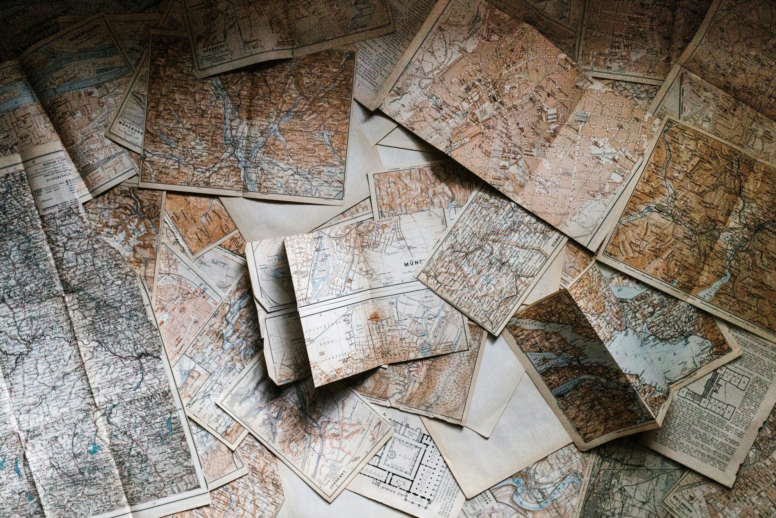 Old, weathered maps scattered on a surface.