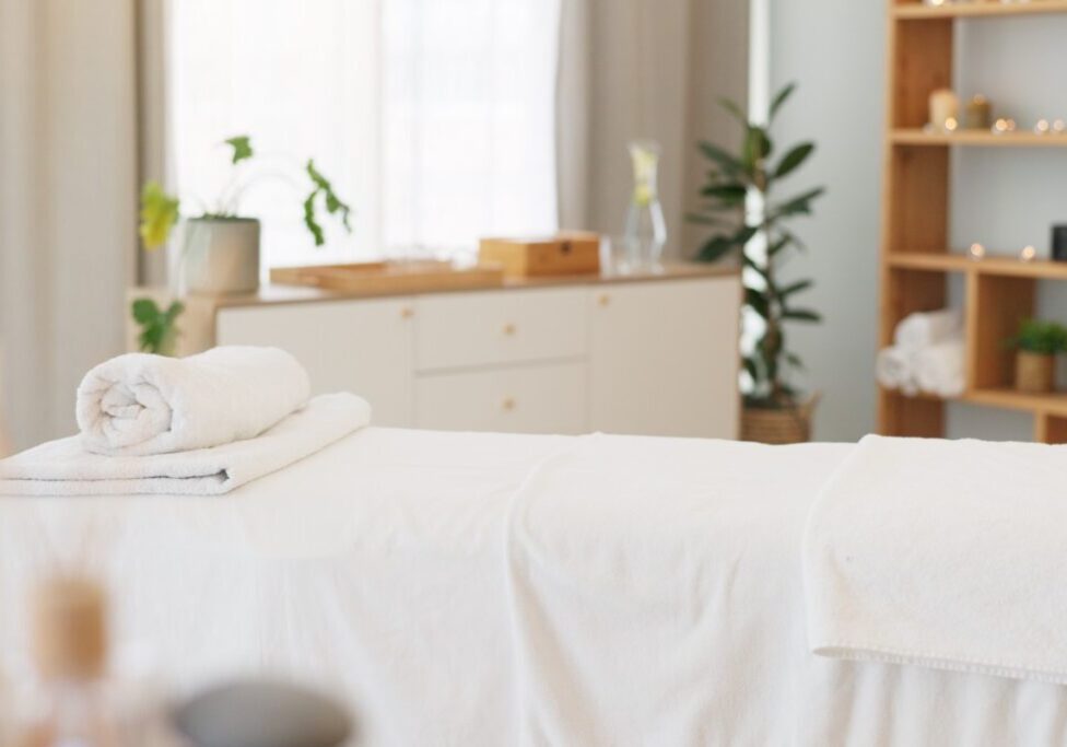 A serene spa room with a massage table and neatly folded towels.