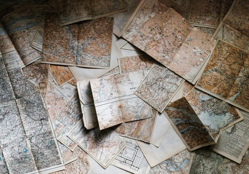 Old, weathered maps scattered on a surface.